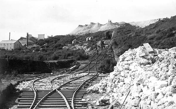Incline on Union Hill, showing the portal of the tunnel which took ore from the New Shaft. What was the gauge, 36"? Note the lower tailings bund at left of picture, the pile of rubble for ballasting the line, and the small dwellings at top centre. Picture taken from near the "gorge" on the walkway